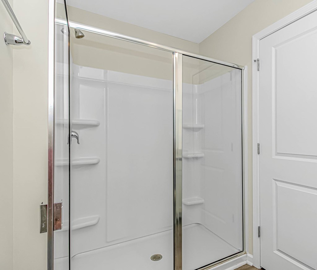 A white bathroom with a glass shower door.