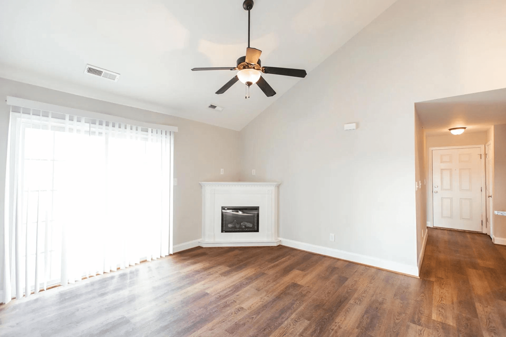an empty living room with a ceiling fan and a fireplace