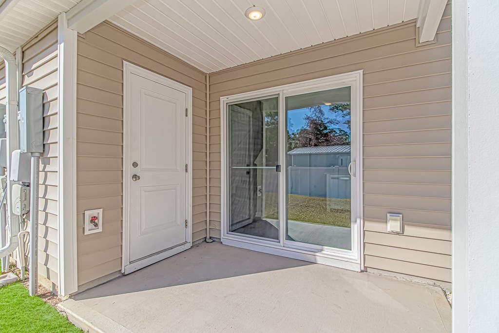 A white door is on the left side of a house with a glass door on the right.