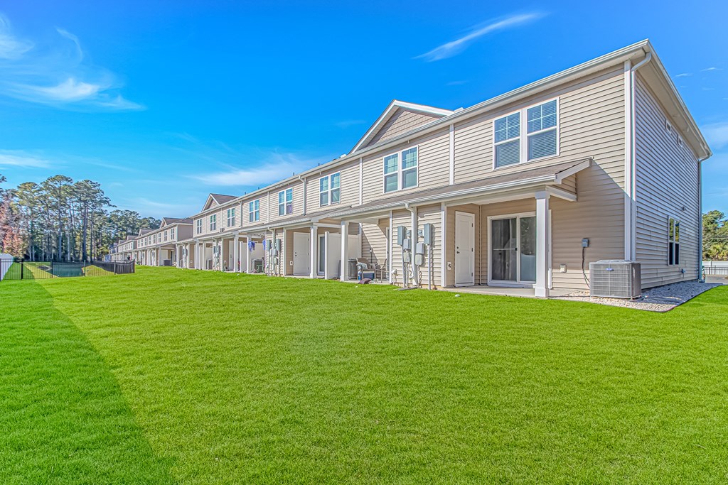 A row of houses with green lawns in front.