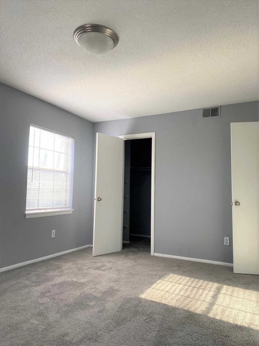 an empty room with a door open to a closet and a window