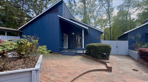 A blue house with a white fence and a brick walkway.