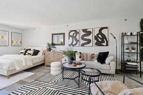 A modern living room with a white sofa, a black and white rug, and a wooden coffee table.