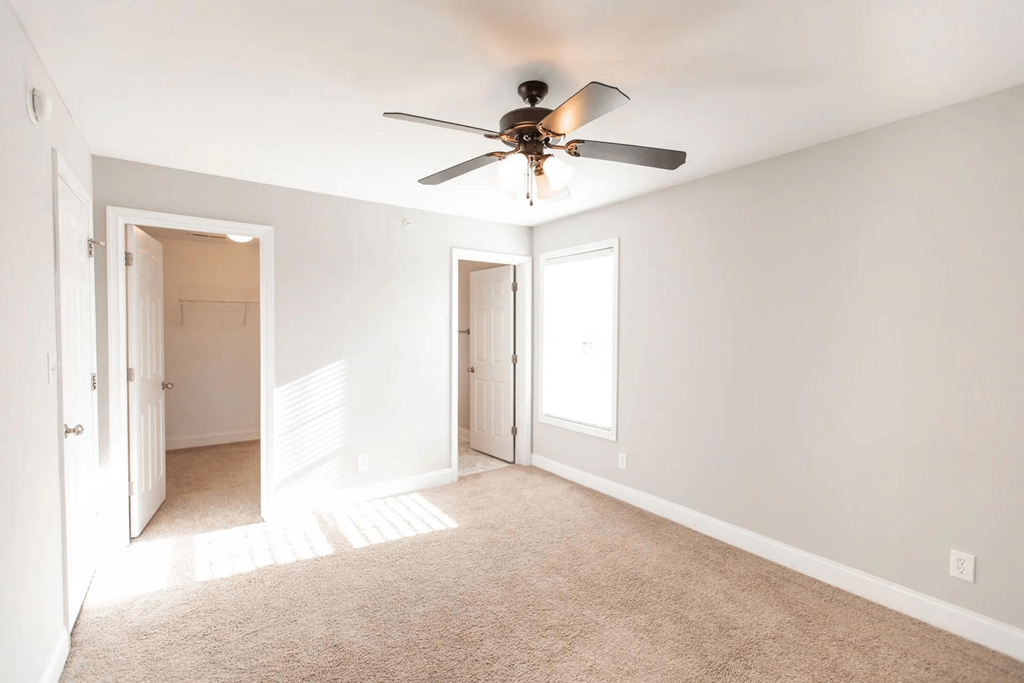 an empty living room with a ceiling fan