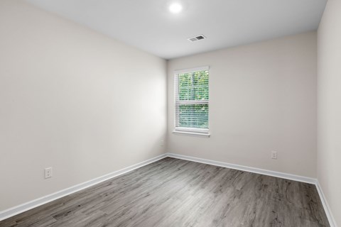 A room with a window and wooden flooring.