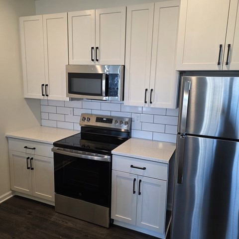 A kitchen with white cabinets and a stainless steel refrigerator.