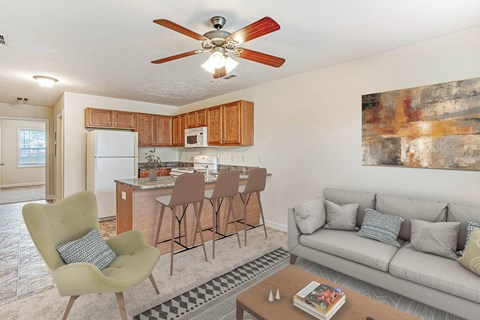 A living room with a grey couch, a green chair, and a brown bar stool.