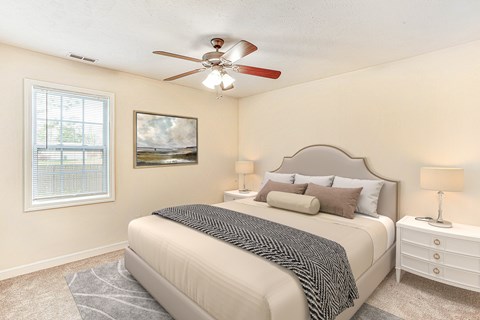 A bedroom with a bed, nightstand, and a ceiling fan.