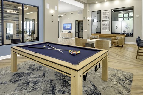A pool table with a blue cloth and white balls is in the center of the room.