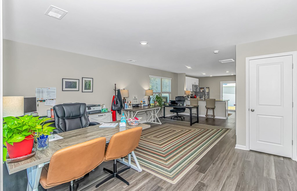 A room with a desk, chairs, and a potted plant.