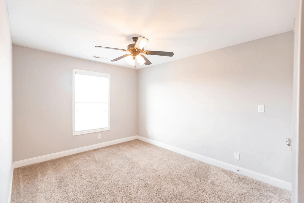 an empty room with a ceiling fan and a window