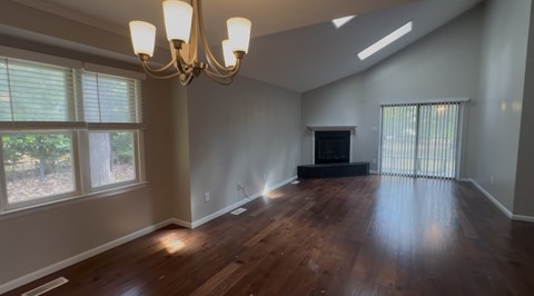 A large empty room with a chandelier and a fireplace.
