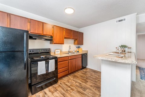 A black stove and oven in a kitchen with wooden floors and white walls.