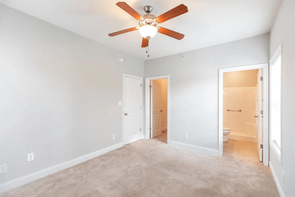 a living room with a ceiling fan and a door to a bathroom