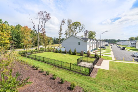 A house is surrounded by a black fence and a grassy area.