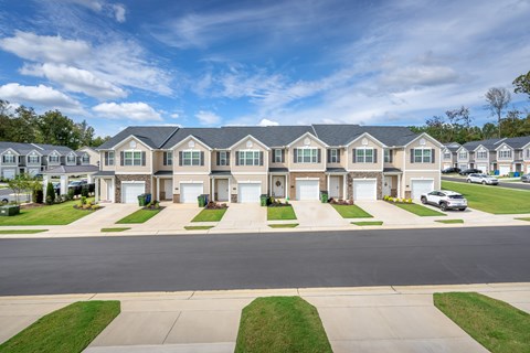 A row of houses with a car parked in front of the first house.