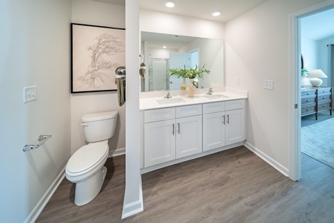 A white bathroom with a toilet, sink, and cabinet.