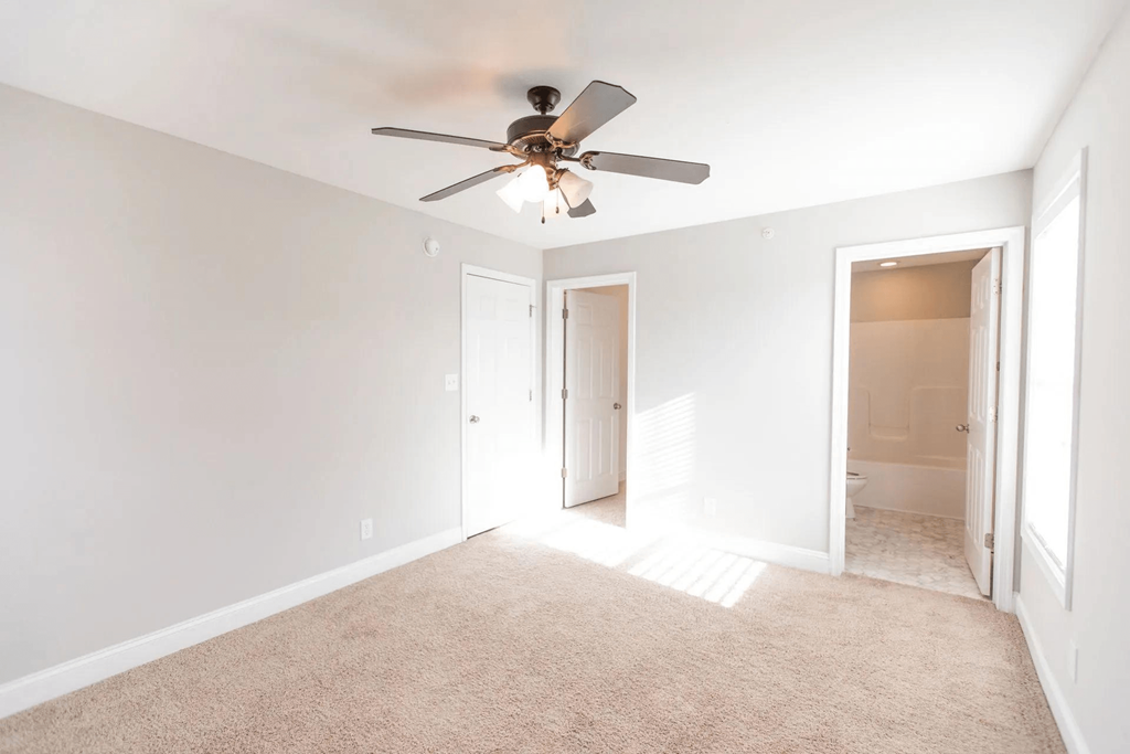 a living room with a ceiling fan and a door to a bathroom