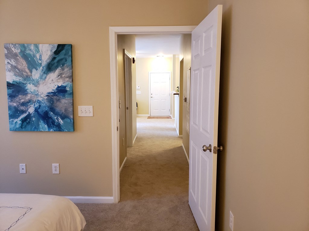 a bedroom with a white bed and a painting on the wall