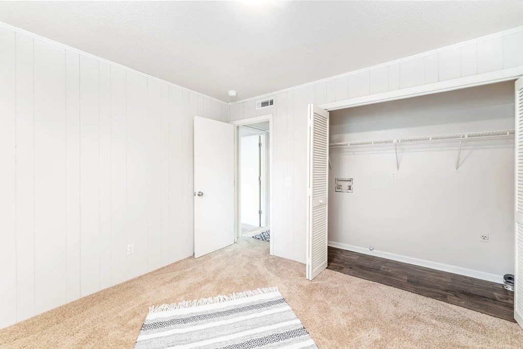 A room with a rug on the floor and a door on the left.