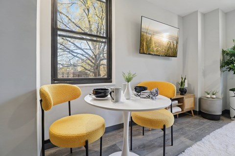 A dining room with a white table and yellow chairs.