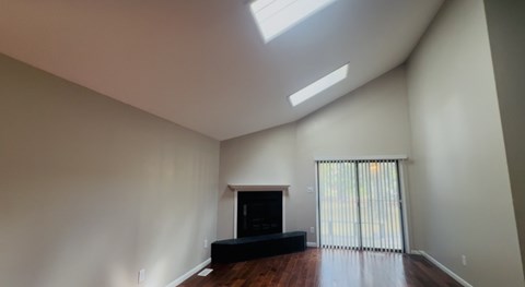 A living room with a fireplace and a skylight.
