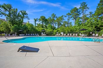 A large outdoor swimming pool surrounded by trees and lounge chairs.