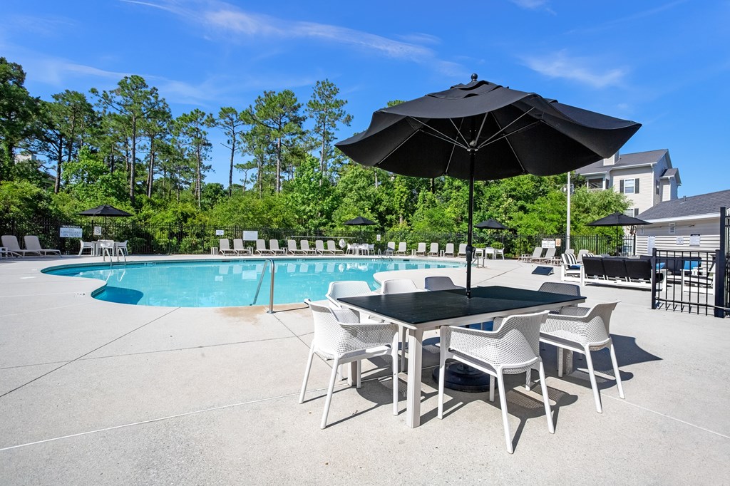 A black umbrella shades a table with four chairs.