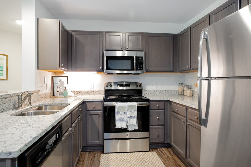 A modern kitchen with a stainless steel refrigerator and black appliances.