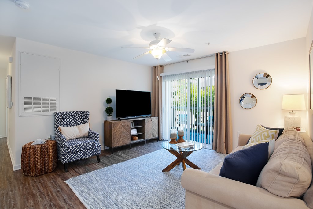A living room with a chair, a sofa, a coffee table, and a television.