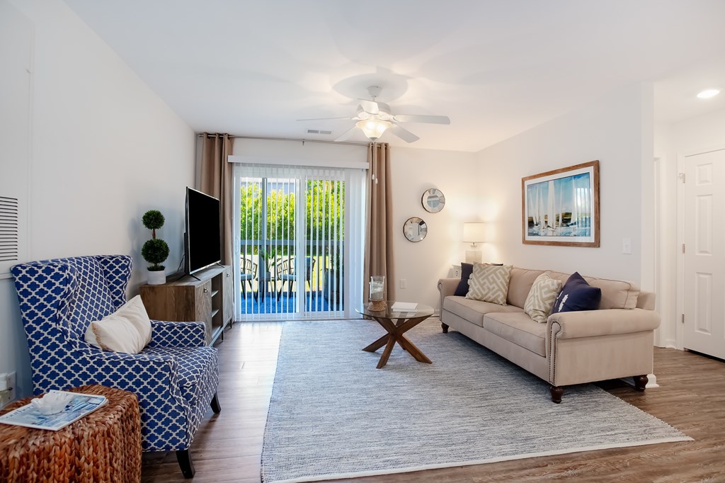 A living room with a blue patterned couch and a beige couch.
