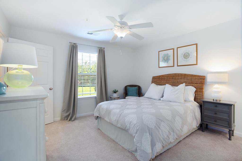 A bedroom with a bed, nightstand, and a ceiling fan.