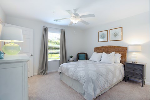 A bedroom with a bed, nightstand, and a ceiling fan.