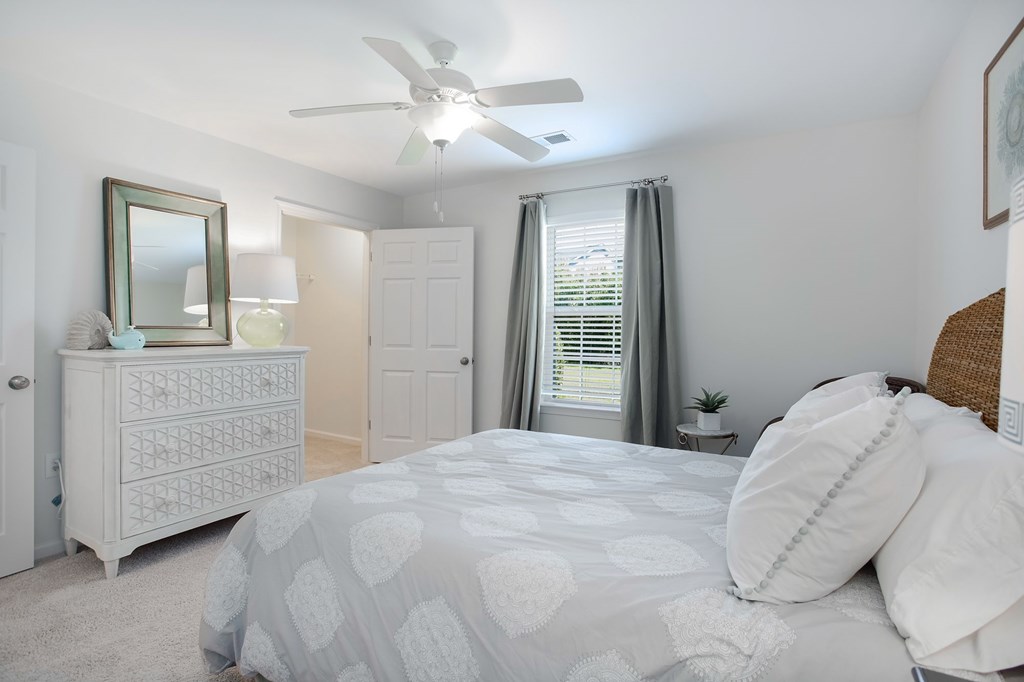 A bedroom with a bed, dresser, and mirror.