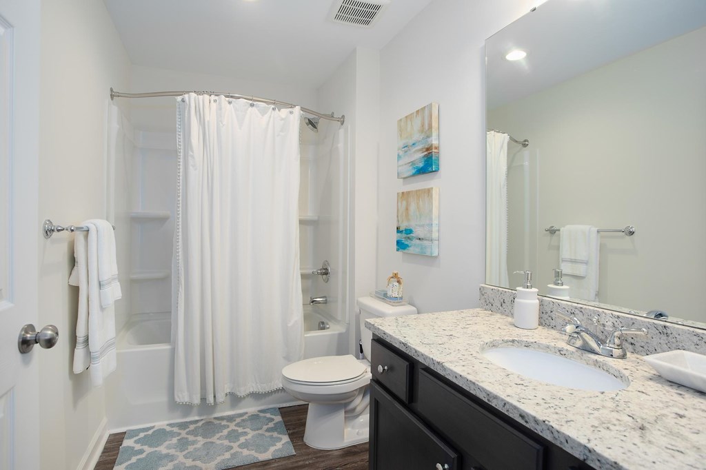 A white bathroom with a toilet, sink, and shower.