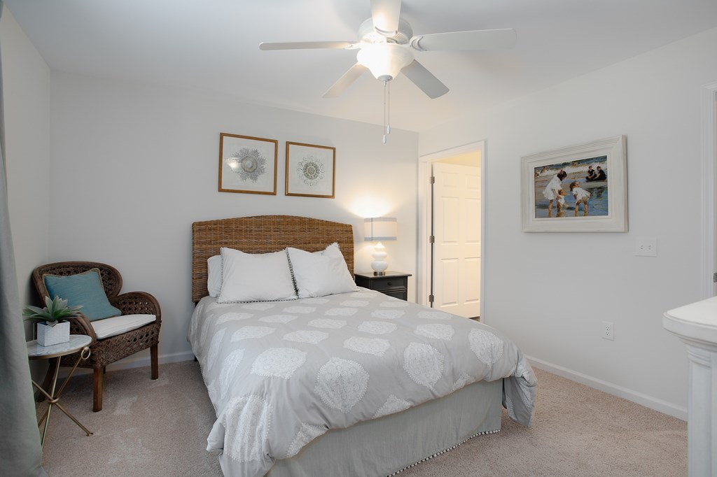 A bedroom with a bed, chair, and pictures on the wall.