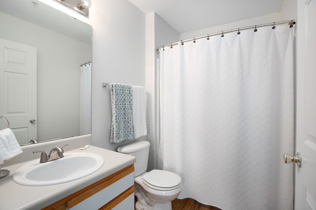 A white bathroom with a toilet, sink, and shower.