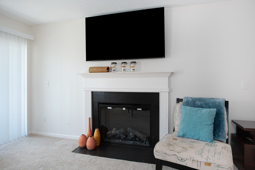 A living room with a fireplace, a sofa and a television mounted above it.
