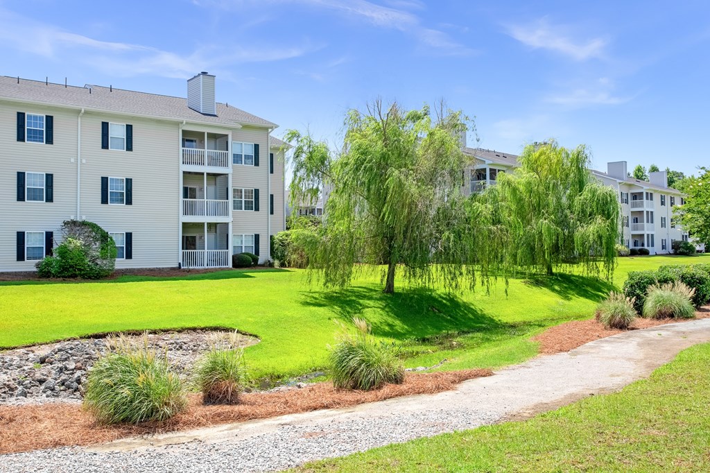 A white apartment building with a green lawn in front.