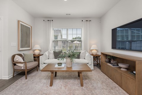 A living room with a white couch, a wooden coffee table, and a painting on the wall.