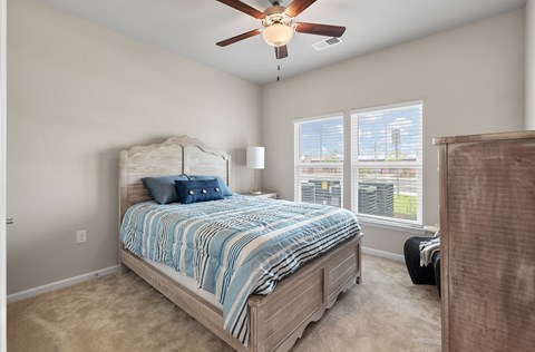 A bedroom with a large bed and a ceiling fan.
