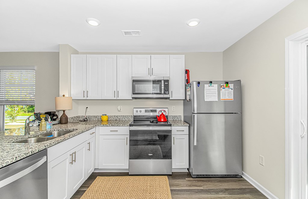 A kitchen with a refrigerator, microwave, and oven.
