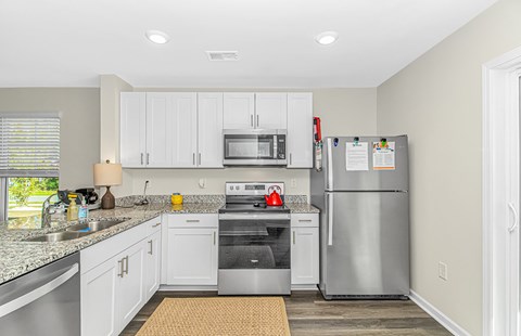A kitchen with a refrigerator, microwave, and oven.