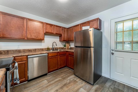 A kitchen with wooden cabinets and a stainless steel refrigerator.