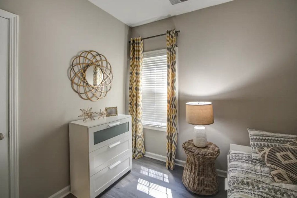 a bedroom with a bed and a dresser in front of a window