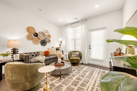 A living room with a grey couch, a green armchair, a coffee table, and a large decorative wall piece.