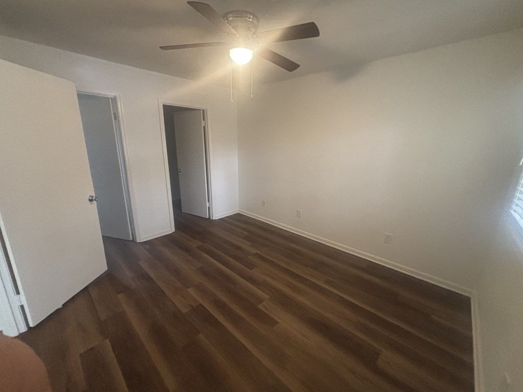 A room with a ceiling fan and wooden flooring.