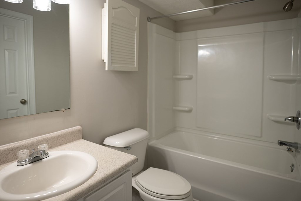 A white bathroom with a toilet, sink, and bathtub.