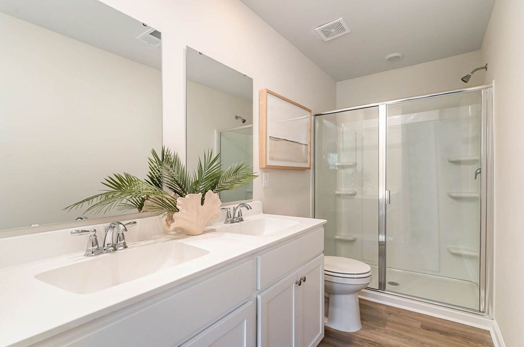 A bathroom with a white sink and a glass shower stall.
