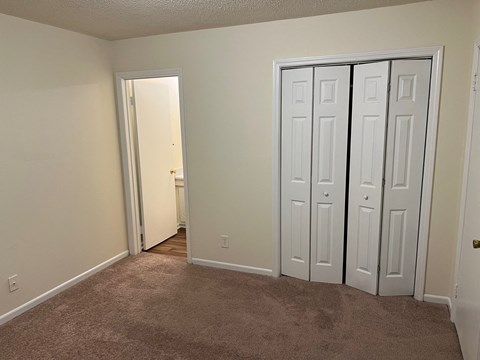 a bedroom with three closets and a carpeted floor